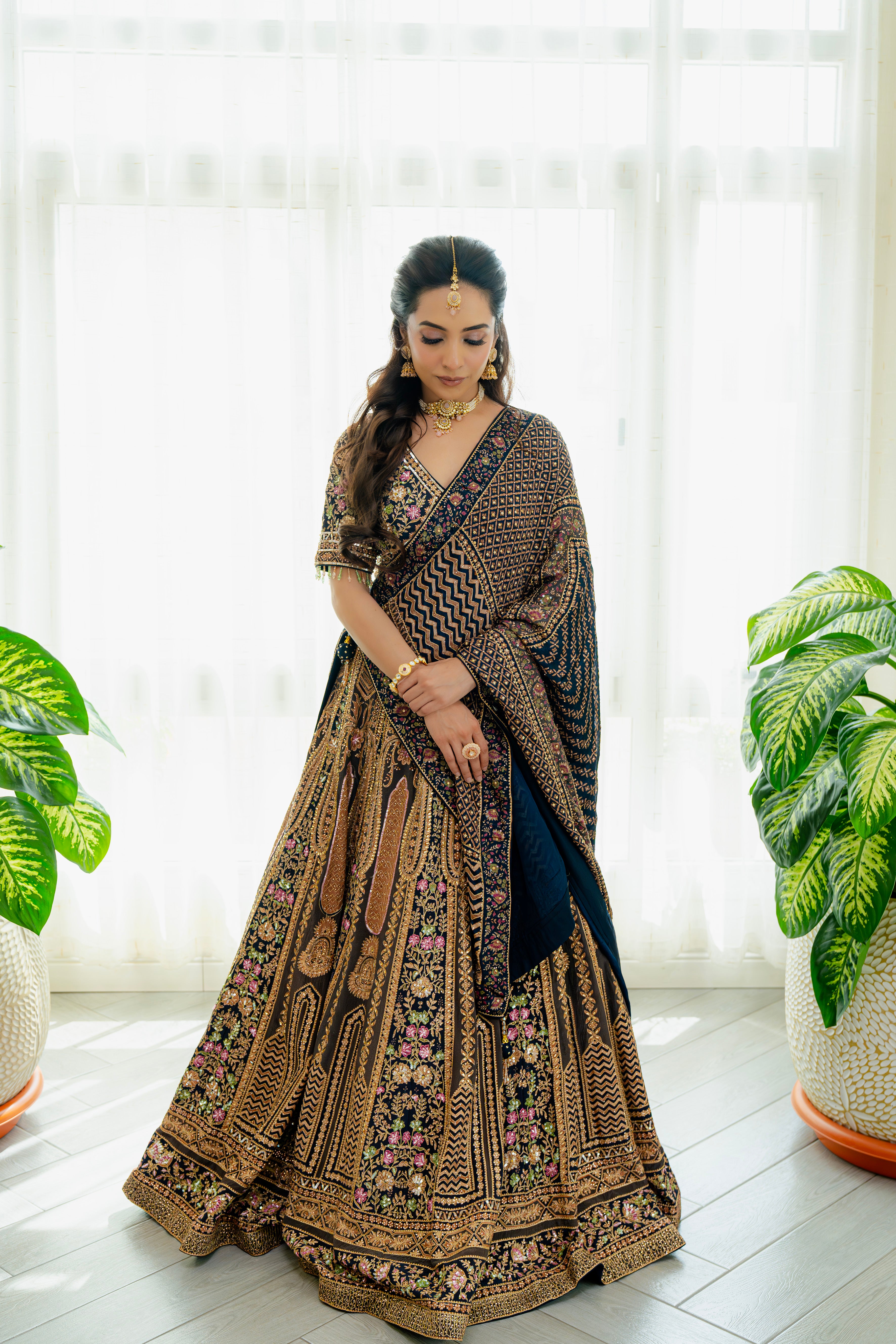 Woman wearing a deep brown embroidered bridal lehenga with floral detailing, styled with a matching dupatta, perfect for weddings and festive occasions.