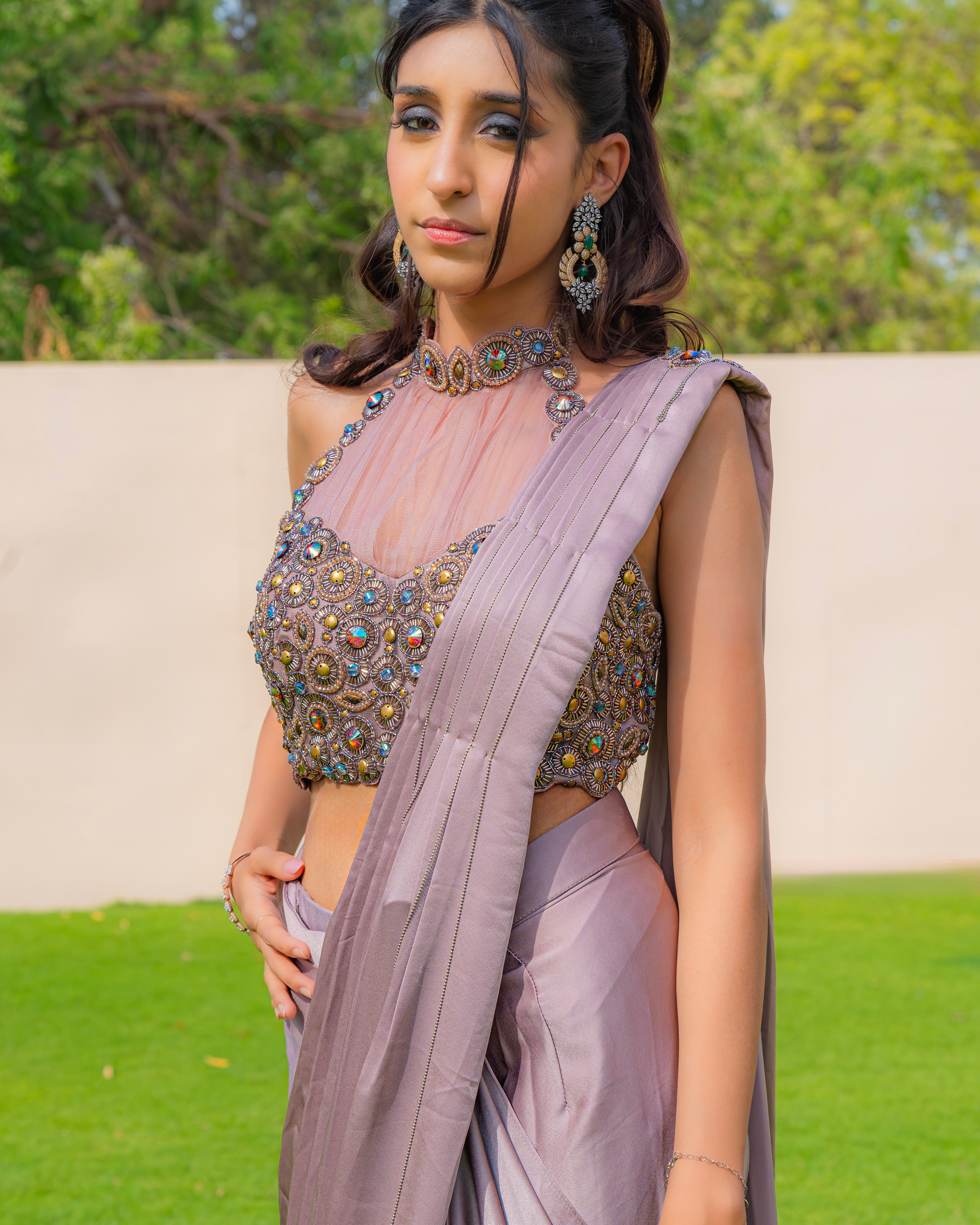 Woman wearing an onion purple ready-to-wear saree styled with a jewelled halter neck pleated blouse, perfect for festive and formal occasions.