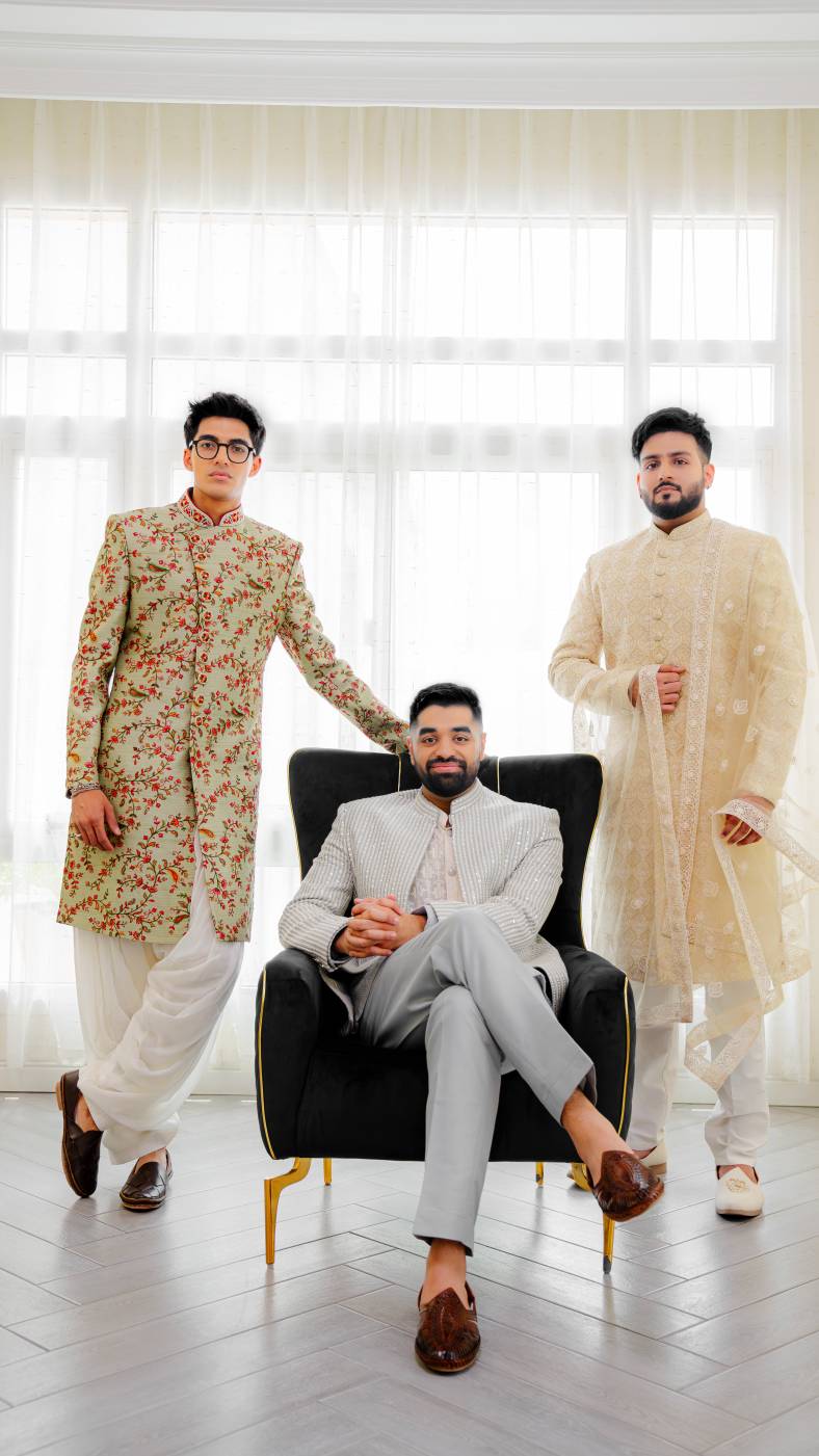 Three men in traditional attire standing in a well-lit room with large windows.
