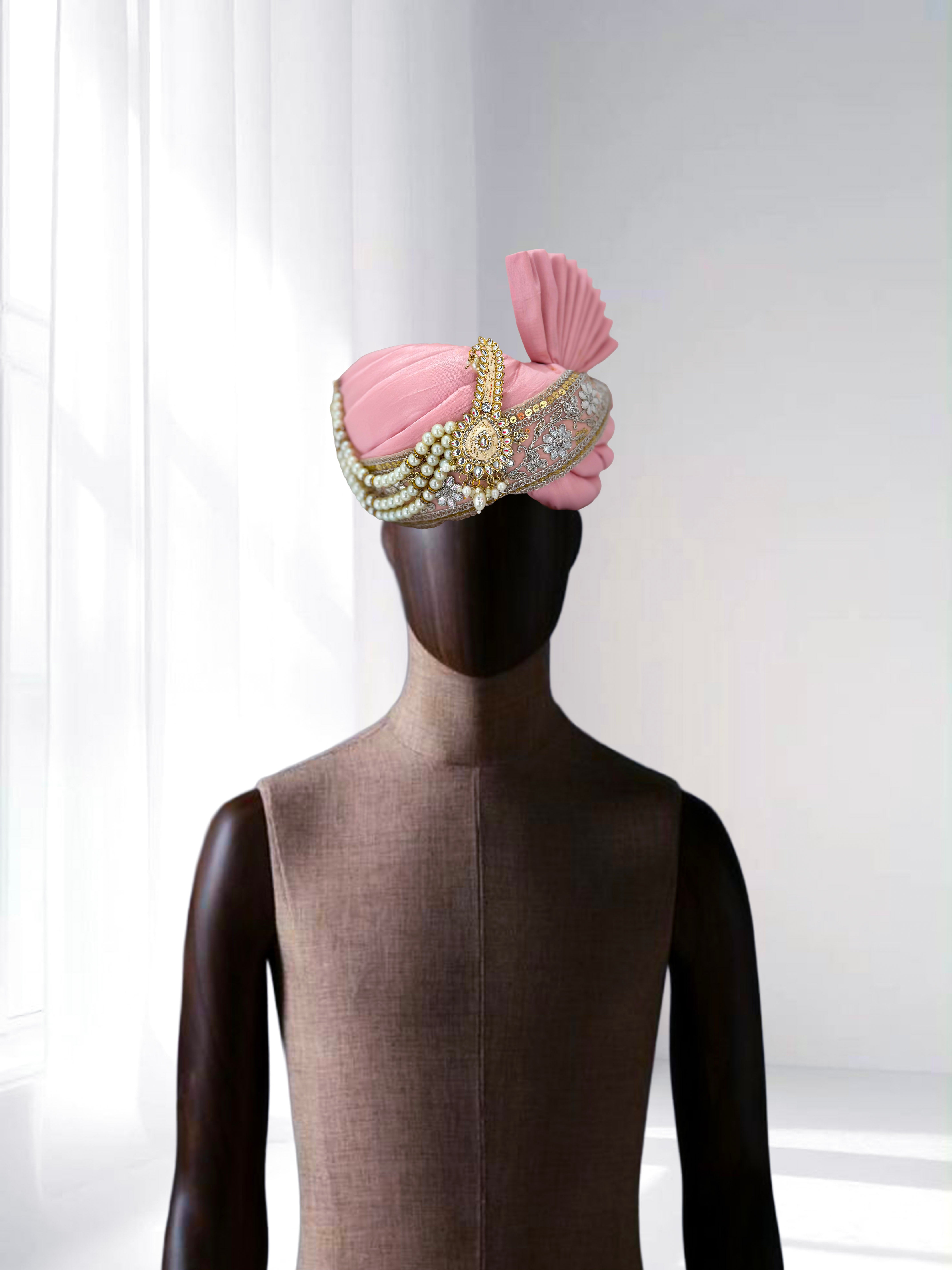 Pastel pink embroidered safa with pearl and gold detailing, traditional groom wedding headwear displayed on mannequin