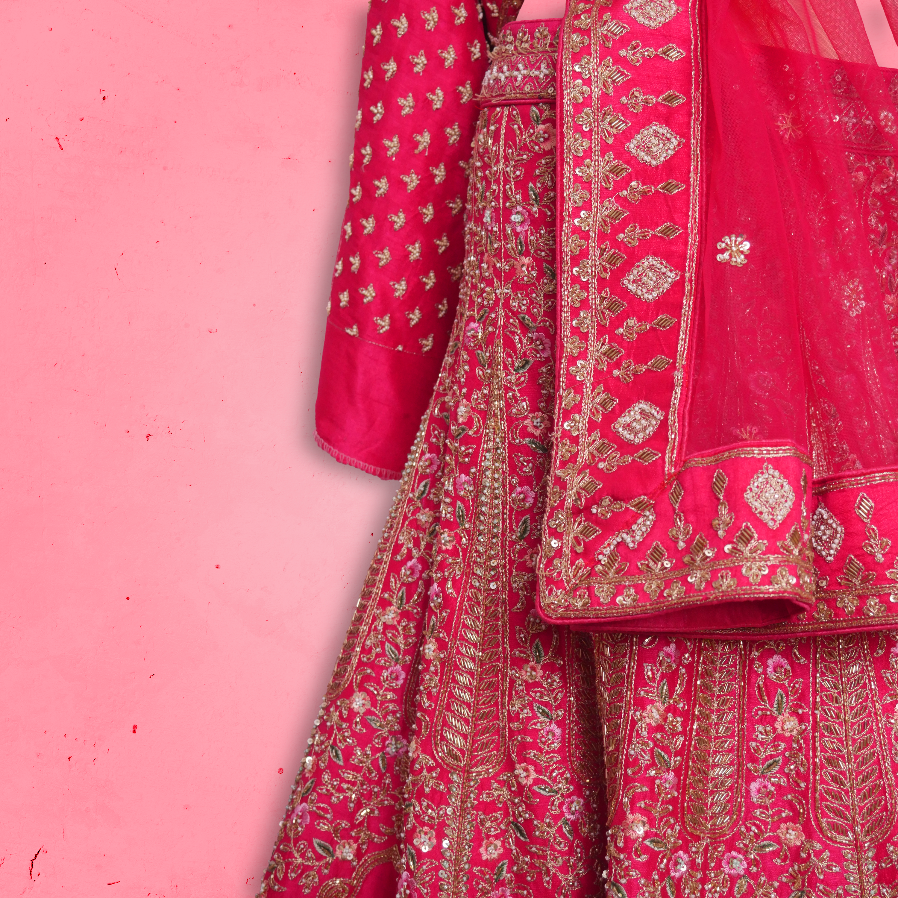 Unstitched rani pink net lehenga set with zari and sequin embroidery, paired with matching embroidered dupatta.