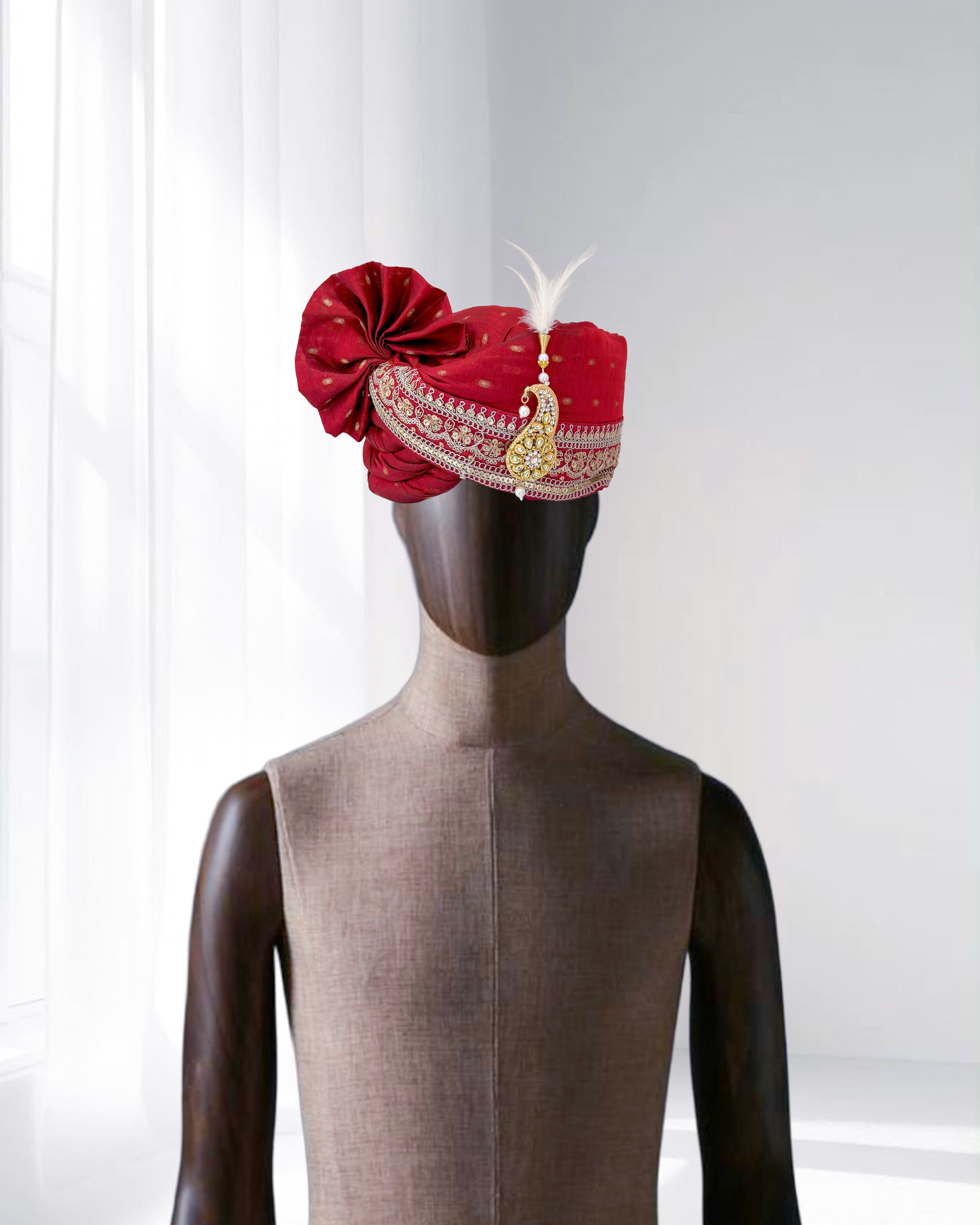 Red wedding groom safa with feather and gold brooch embroidery, traditional Indian turban.