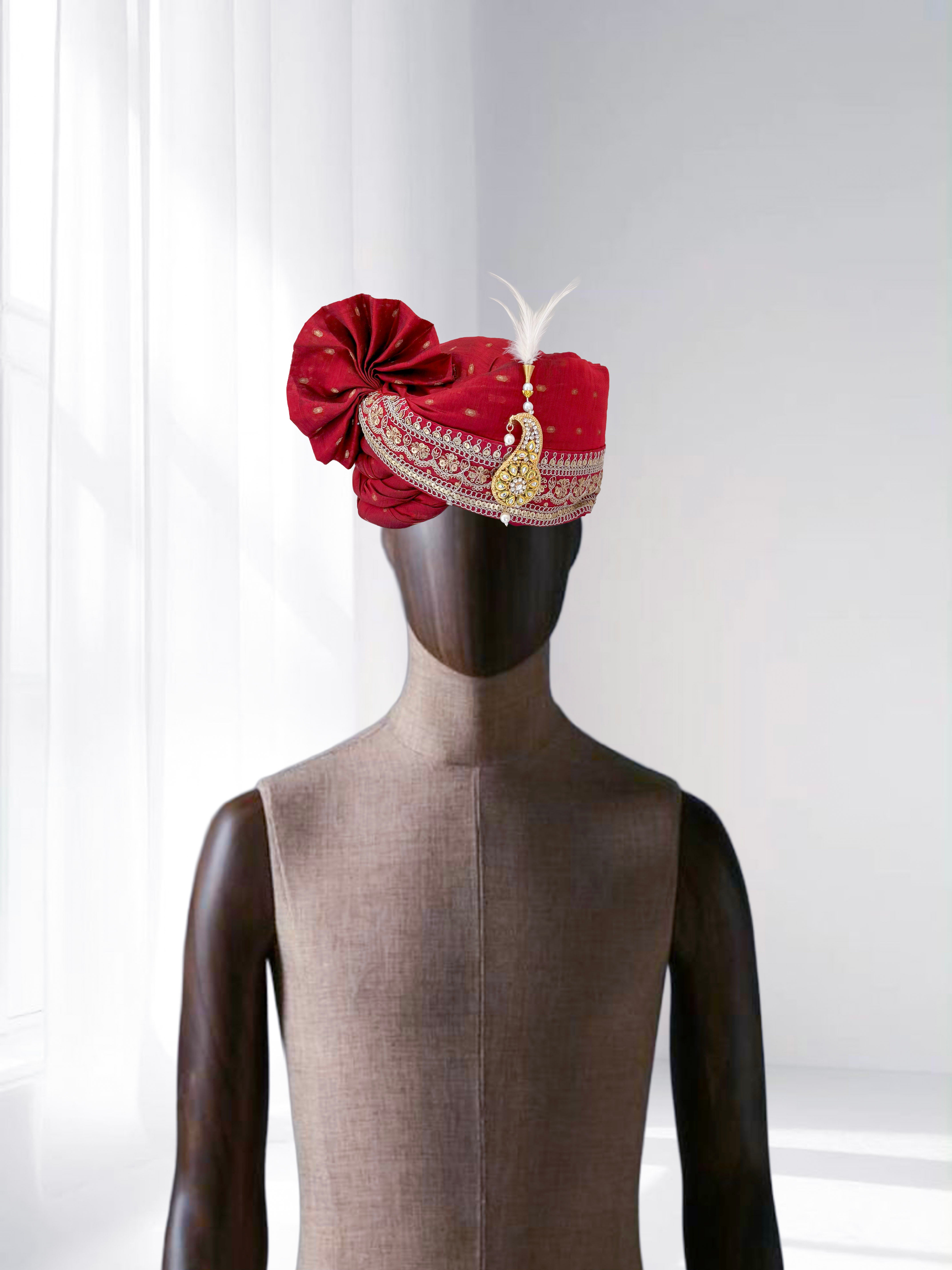 Red wedding groom safa with feather and gold brooch embroidery, traditional Indian turban.