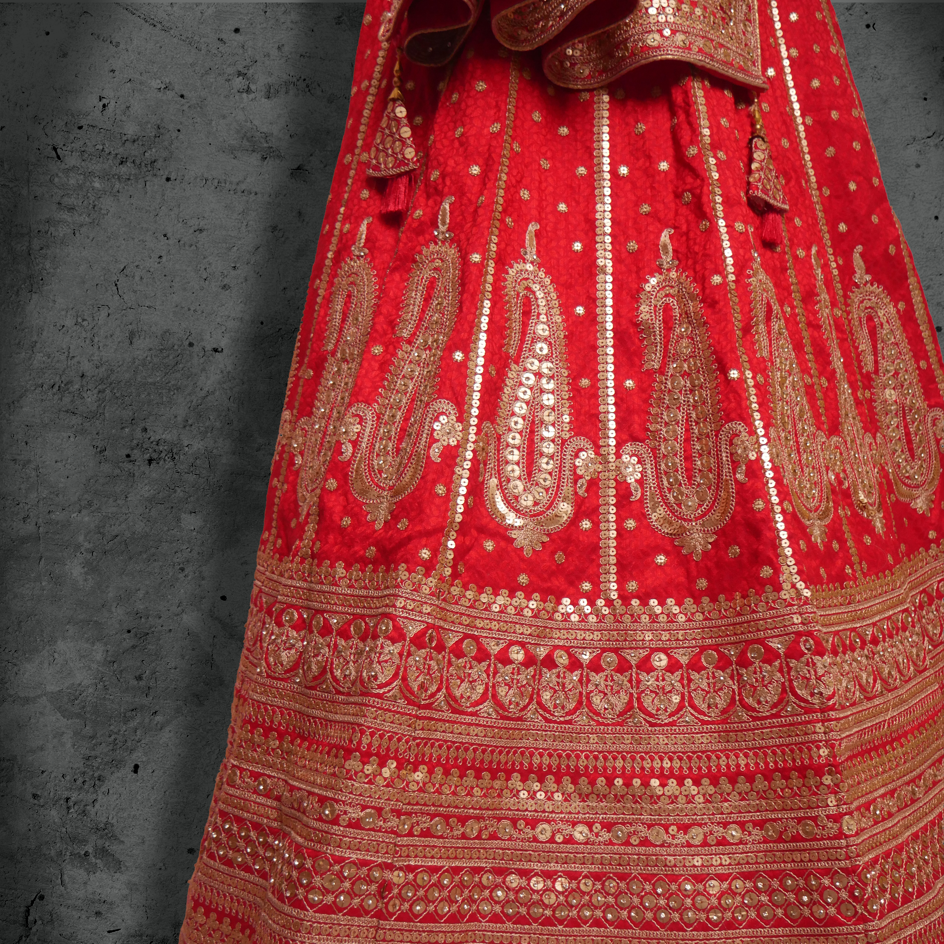 Unstitched red silk bridal lehenga with dense sequin and zari embroidery, paired with a matching net dupatta.