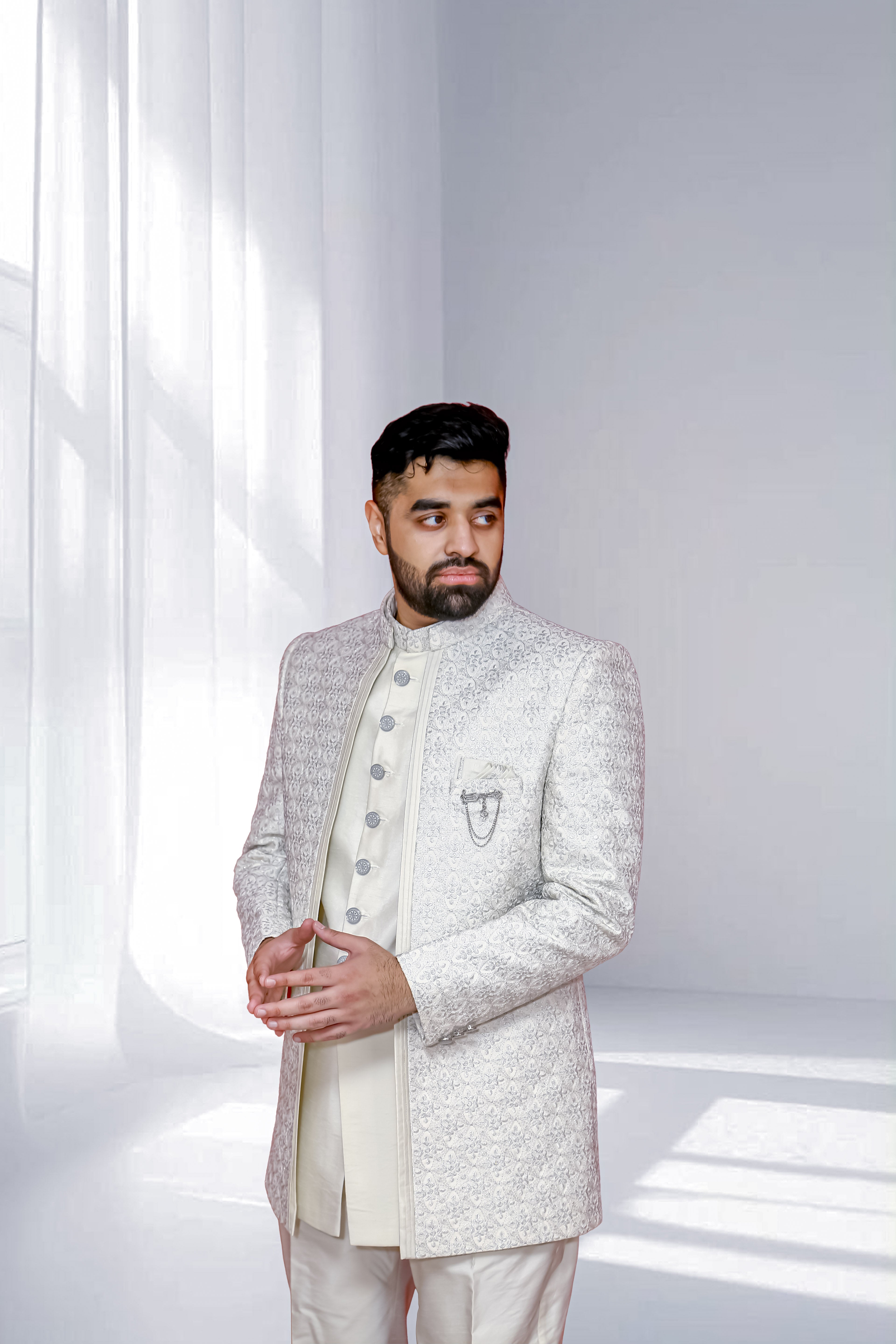 Man wearing a traditional sherwani against a white background