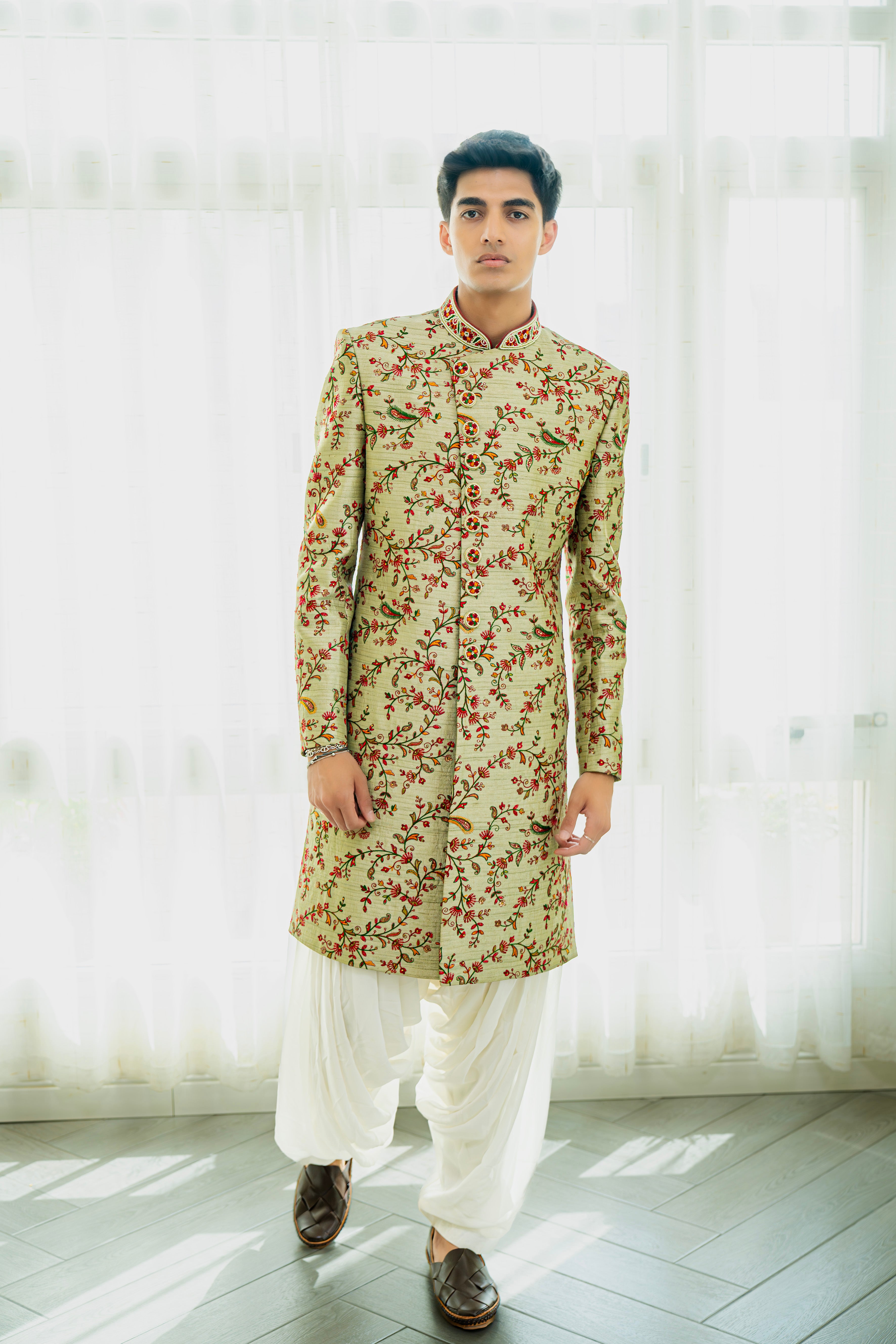 Man wearing a floral kurta with white pants against a light background