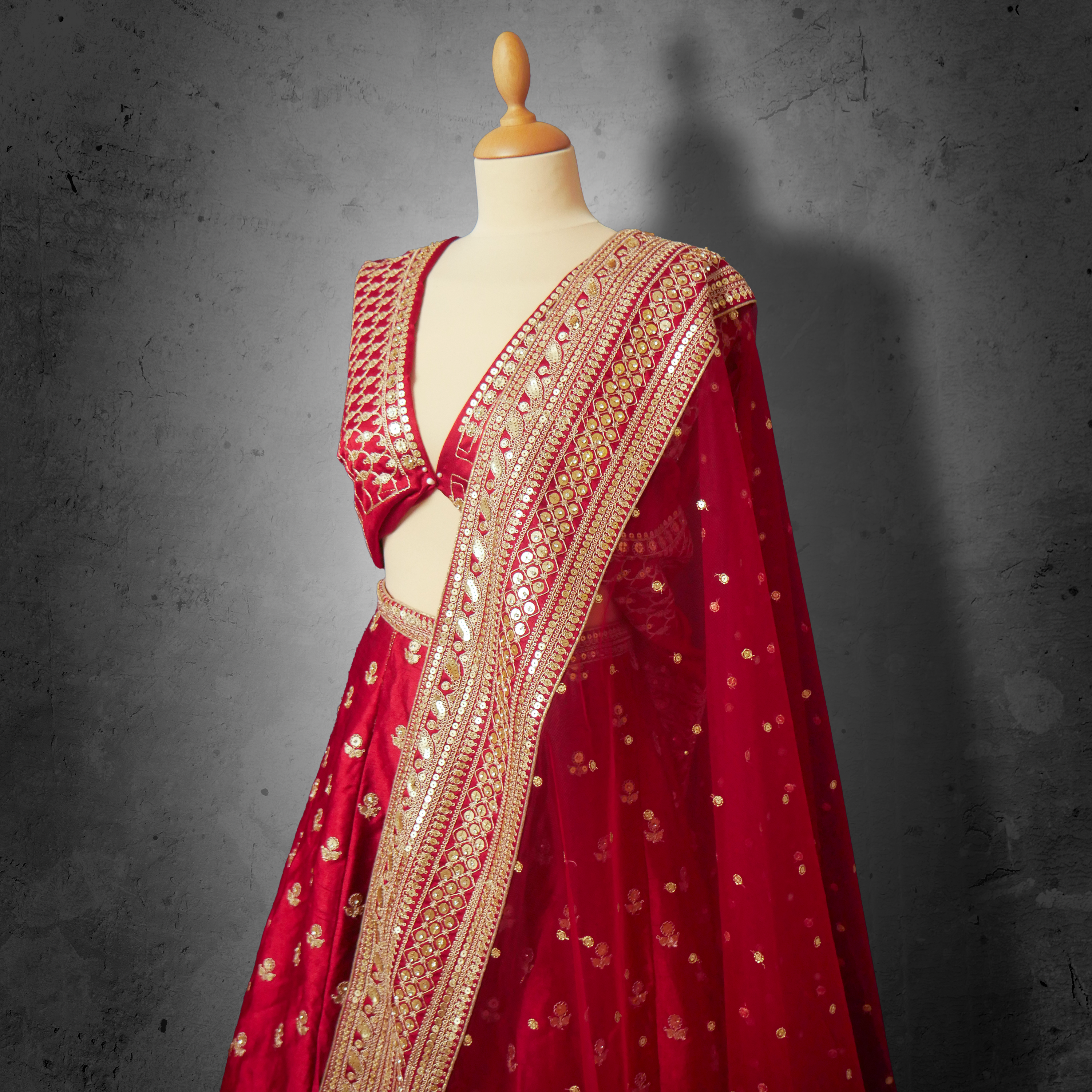 Unstitched red net bridal lehenga with gold zari and sequin embroidery, paired with matching dupatta featuring ornate border
