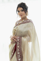 Woman wearing a traditional beige saree with intricate patterns on a white background