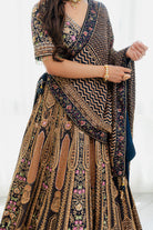 Woman wearing a deep brown embroidered bridal lehenga with floral detailing, styled with a matching dupatta, perfect for weddings and festive occasions.