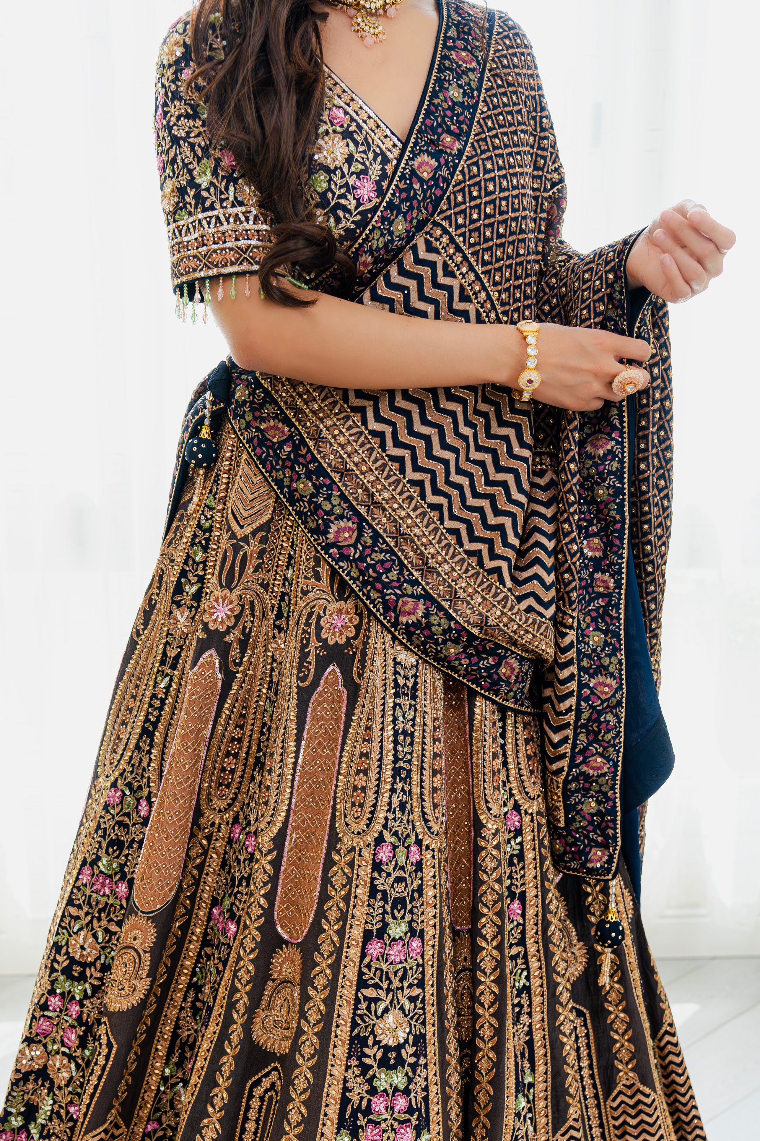 Woman wearing a deep brown embroidered bridal lehenga with floral detailing, styled with a matching dupatta, perfect for weddings and festive occasions.