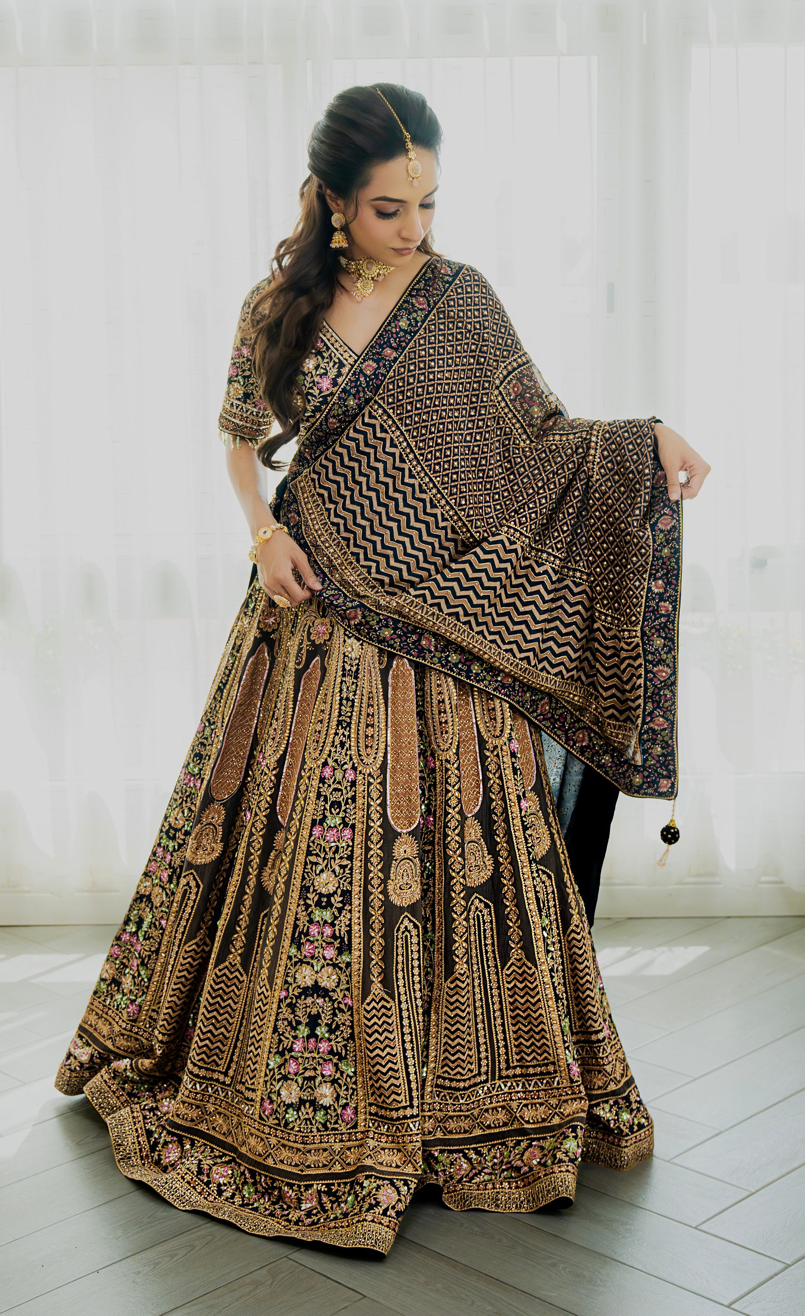 Woman wearing a deep brown embroidered bridal lehenga with floral detailing, styled with a matching dupatta, perfect for weddings and festive occasions.