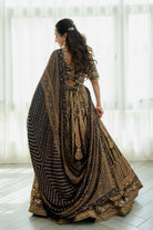 Woman wearing a deep brown embroidered bridal lehenga with floral detailing, styled with a matching dupatta, perfect for weddings and festive occasions.