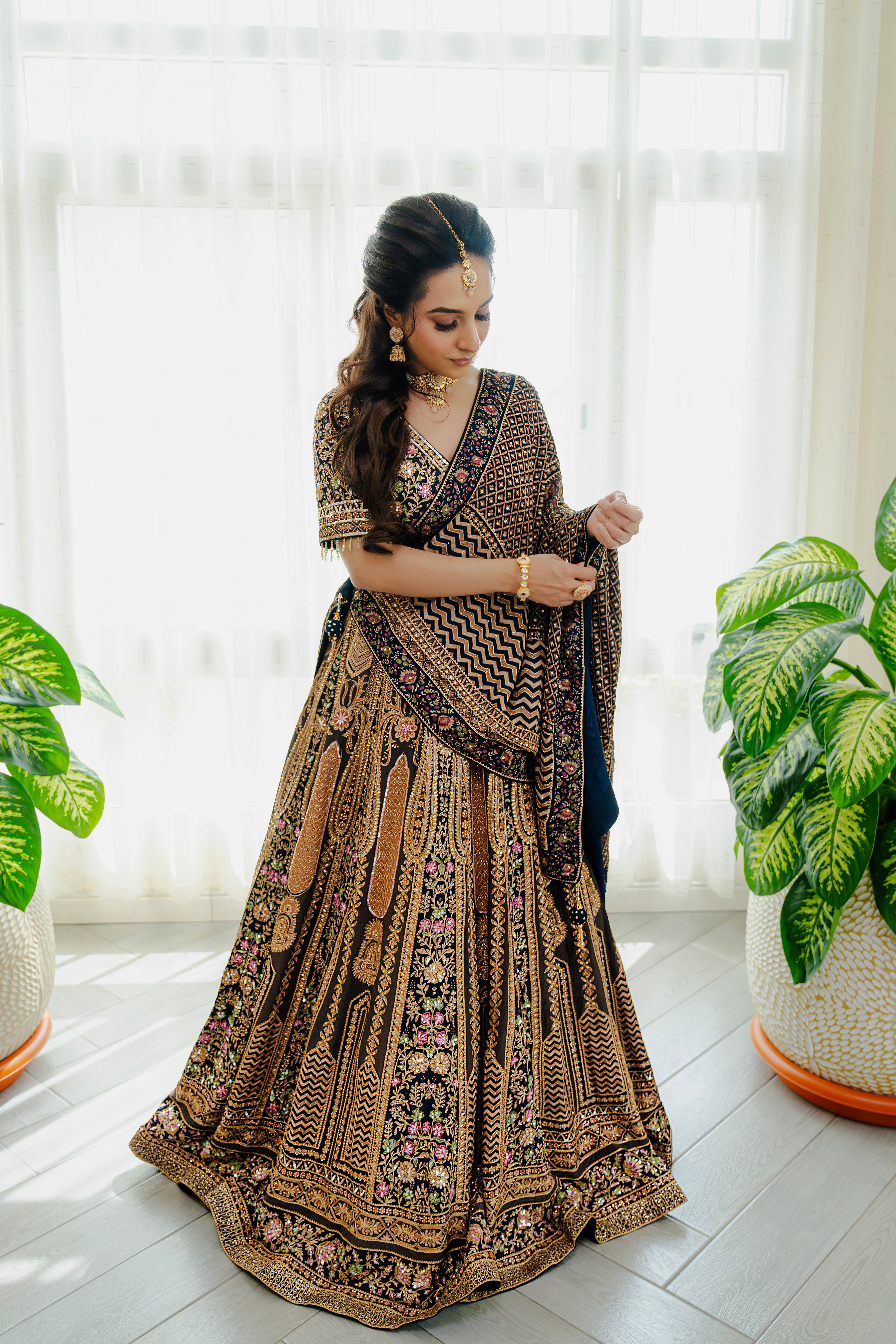 Woman wearing a deep brown embroidered bridal lehenga with floral detailing, styled with a matching dupatta, perfect for weddings and festive occasions.