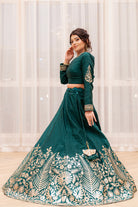 Woman wearing a green embroidered traditional outfit against a white curtain background