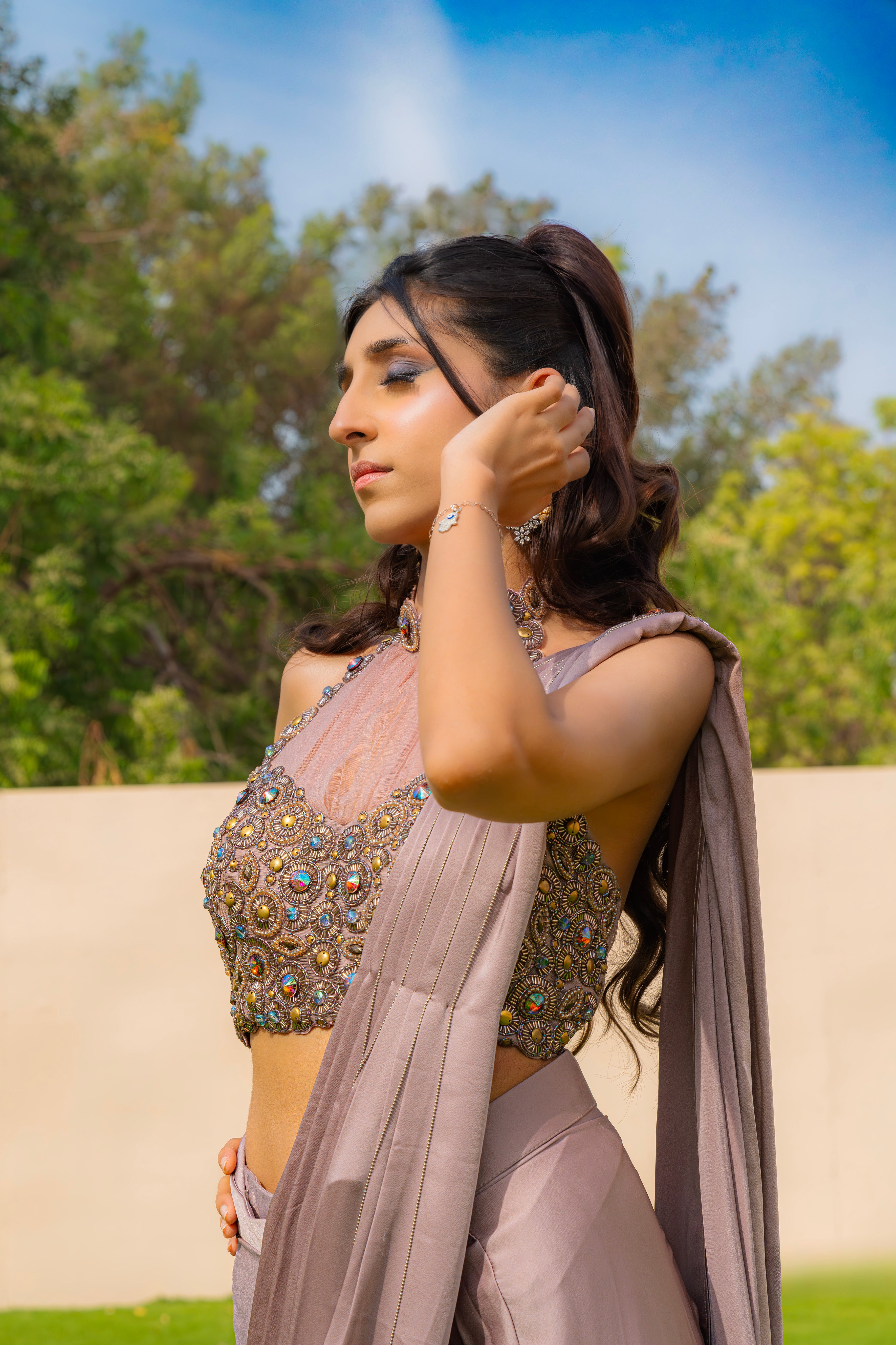 Woman wearing an onion purple ready-to-wear saree styled with a jewelled halter neck pleated blouse, perfect for festive and formal occasions.