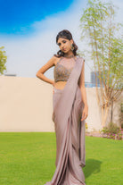 Woman wearing an onion purple ready-to-wear saree styled with a jewelled halter neck pleated blouse, perfect for festive and formal occasions.