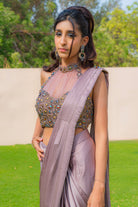 Woman wearing an onion purple ready-to-wear saree styled with a jewelled halter neck pleated blouse, perfect for festive and formal occasions.