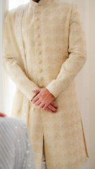 Beige embroidered traditional outfit with a plain background close-up