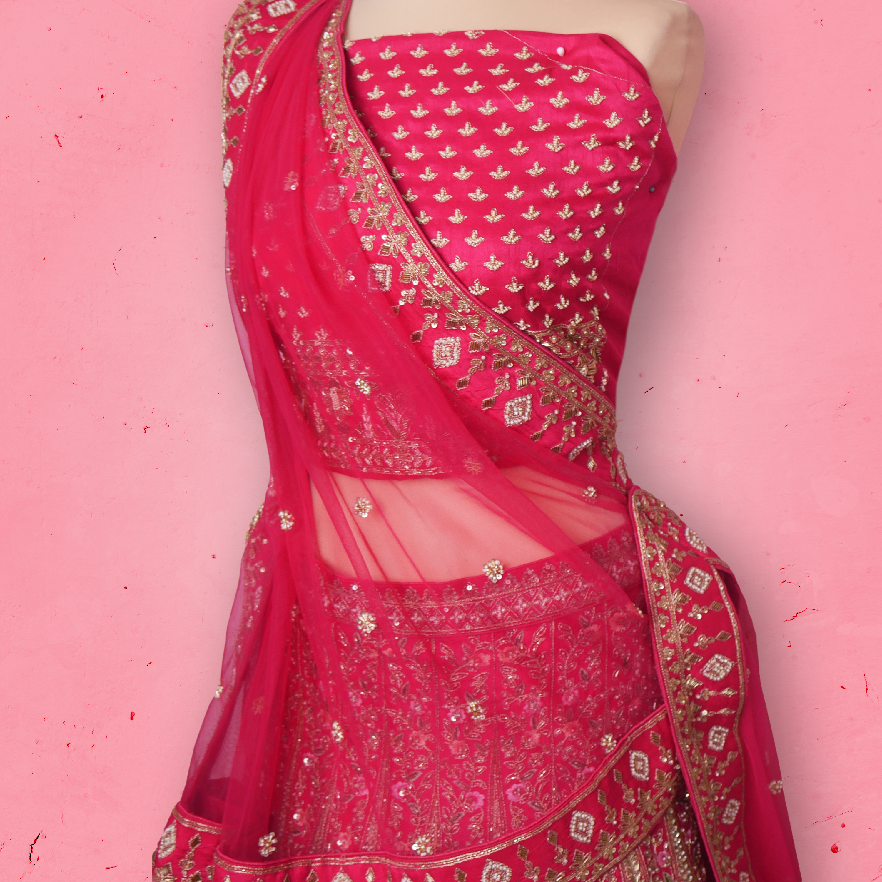 Unstitched rani pink net lehenga set with zari and sequin embroidery, paired with matching embroidered dupatta