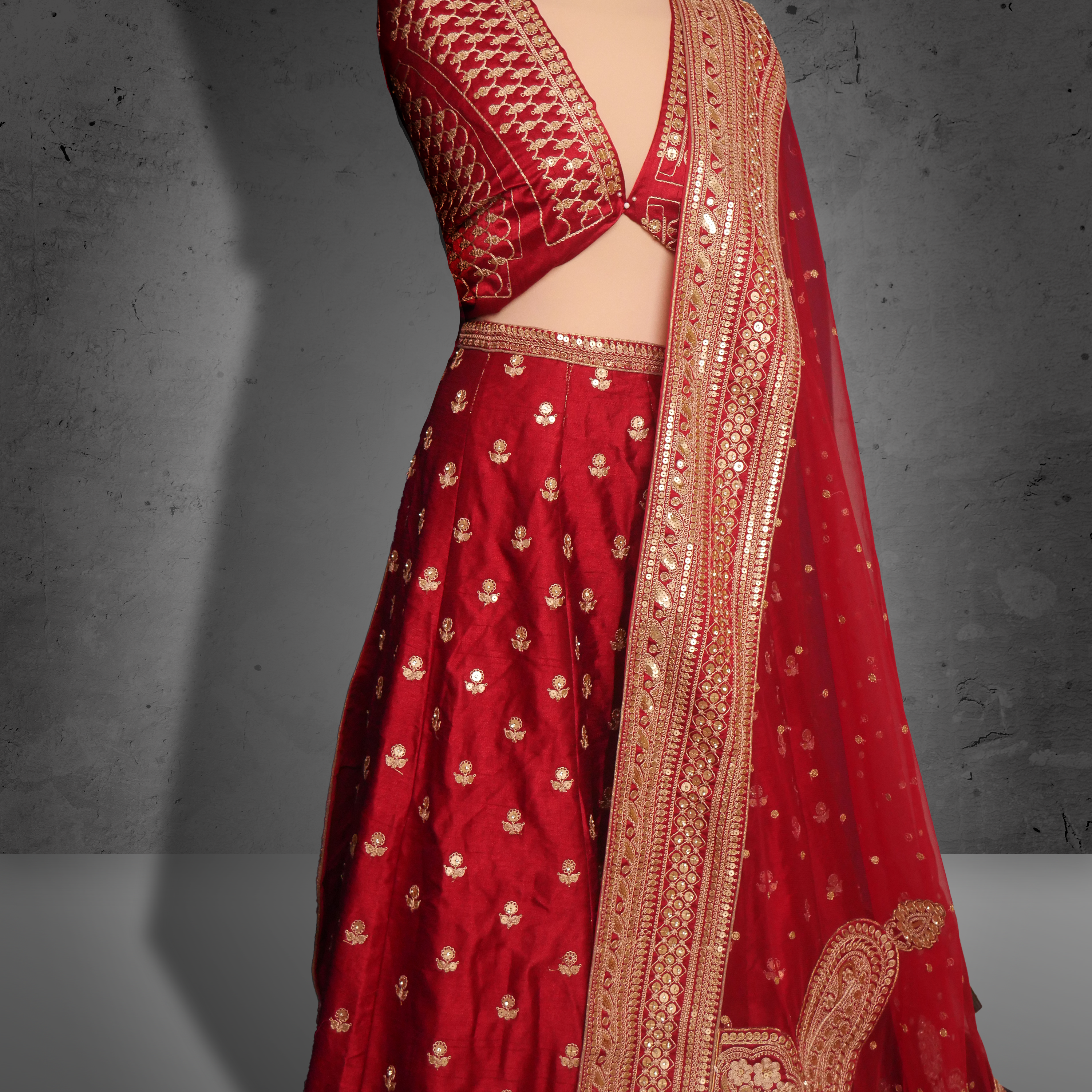 Unstitched red net bridal lehenga with gold zari and sequin embroidery, paired with matching dupatta featuring ornate border.