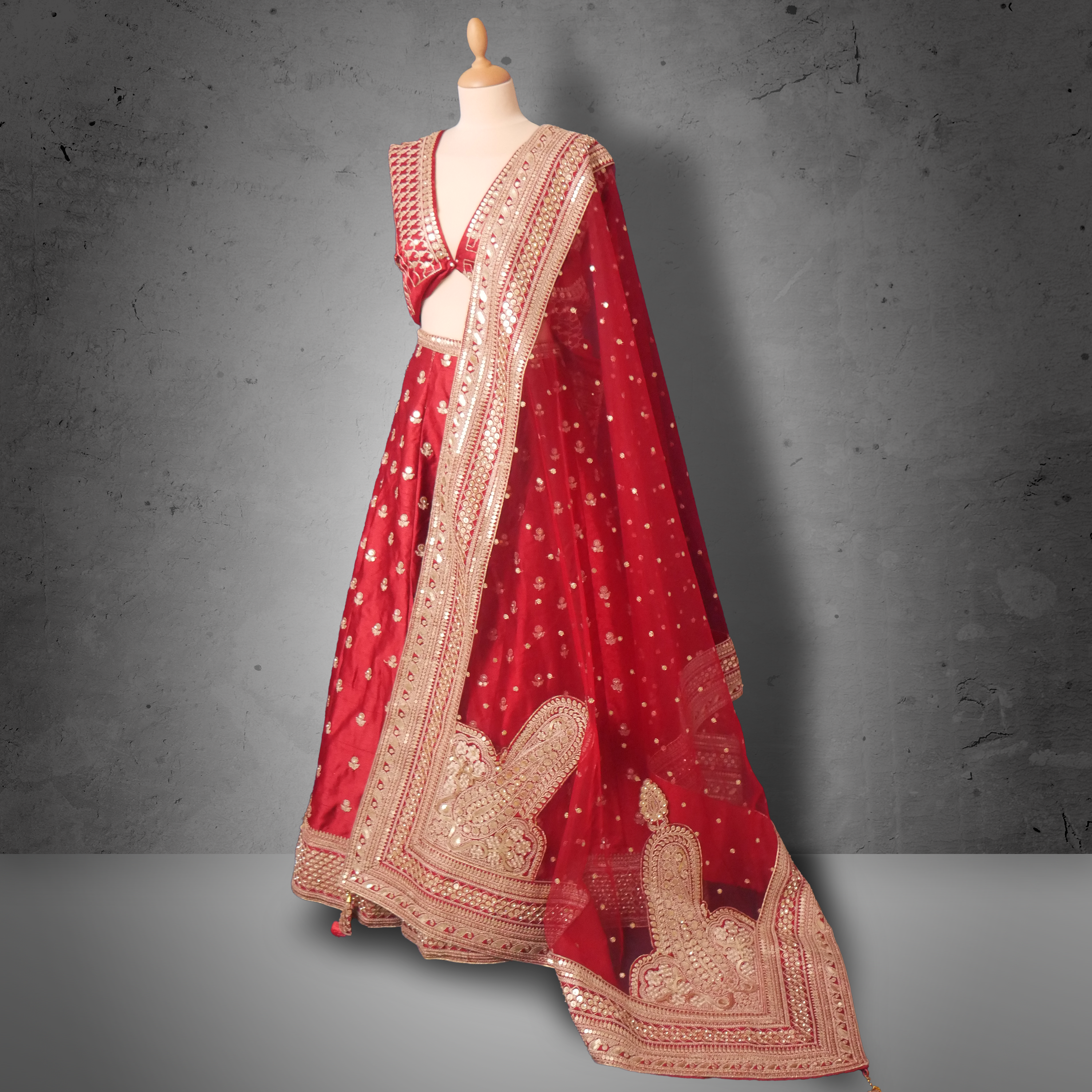 Unstitched red net bridal lehenga with gold zari and sequin embroidery, paired with matching dupatta featuring ornate border.